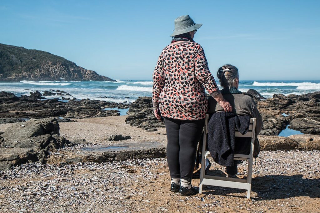 Photo of two women on a beach looking out to sea.