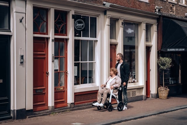 Person pushing a lady in a wheelchair while looking