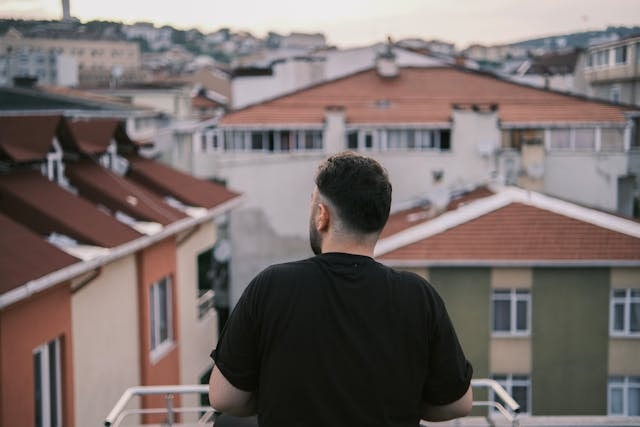 man-on-balcony-looking-on-cityscape