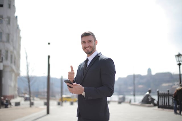 man-in-black-suit-jacket-while-holding-a-smartphone