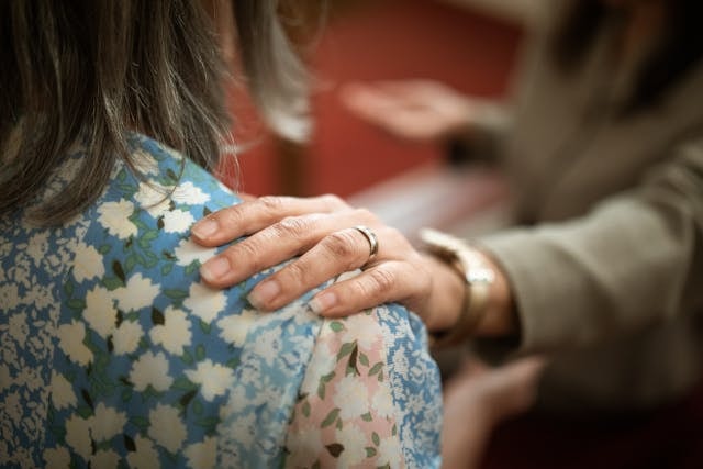 a-person-in-brown-blazer-holding-a-person-s-shoulder