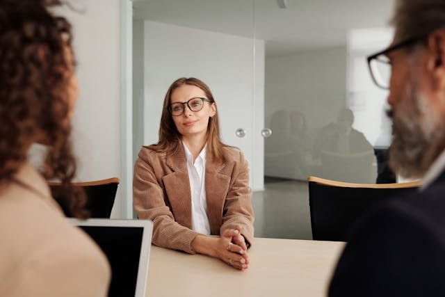 woman-in-brown-blazer-seated-beside-table