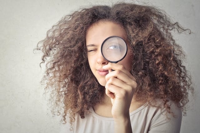 portrait-photo-of-woman-holding-up-a-magnifying-glass-over-her-eye