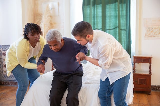 a-man-and-a-woman-assisting-an-elderly-man-in-standing